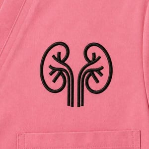 May include: Close-up of a pink scrub top with a black embroidered kidney design. The kidney design is centered on the chest and is a detailed, stylized illustration. The top has a V-neck and a small pocket.