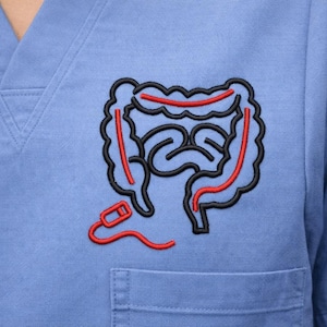 May include: A light blue scrub top with a black and red embroidered design of the human colon. The design is located on the left chest area, above the pocket. The embroidery is detailed and features the colon's shape.