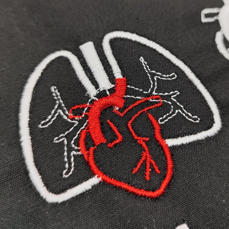 Pu&ograve; includere: Tessuto nero con un ricamo raffigurante un cuore e polmoni anatomici. Il cuore &egrave; rosso e i polmoni sono delineati in bianco. Illustrazione a tema medico o scientifico.