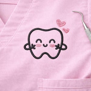 Peut inclure: Un haut de blouse rose clair avec une broderie d'une dent de dessin animé souriante et deux cœurs roses. Un instrument dentaire est visible sur le côté droit. Le haut a une encolure en V et une poche.