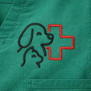 Könnte beinhalten: Grünes medizinisches Scrub-Top mit V-Ausschnitt und Tasche. Das Oberteil hat ein gesticktes Design von zwei Hundeprofilen und einem roten Kreuz, das üblicherweise mit der Tiermedizin in Verbindung gebracht wird. Das Design ist schwarz umrandet.