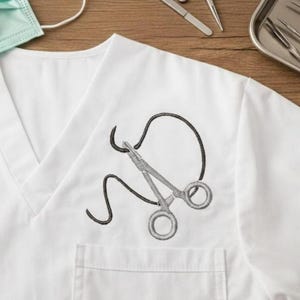 May include: White medical scrub top with a V-neck and a pocket. The top features an embroidered design of surgical scissors and a black outline. A green face mask is visible in the upper left corner.