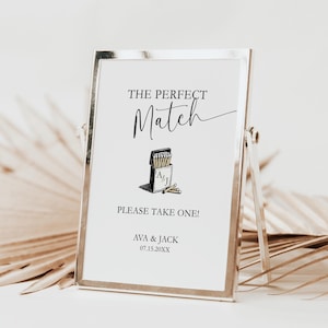 Peut inclure: Un panneau encadré avec l'inscription "THE PERFECT Match" en écriture élégante. En dessous, une illustration d'une boîte d'allumettes avec des allumettes. Le texte "PLEASE TAKE ONE!" et les noms "AVA & JACK" sont également affichés.