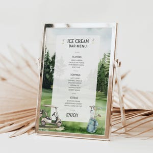 Könnte beinhalten: Ein gerahmtes Eisbar-Menü mit Golfplatz-Thema. Das Menü listet Geschmacksrichtungen, Toppings und Extras auf. Der Hintergrund zeigt einen Golfwagen, eine Golftasche und eine malerische Aussicht auf Bäume. Der Text lautet "ICE CREAM BAR MENU" und "ENJOY".