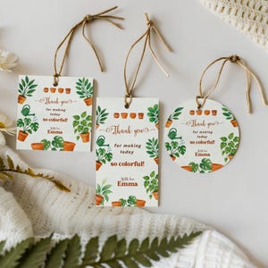 Może przedstawiać: Trzy zawieszki na prezenty z akwarelowymi ilustracjami roślin doniczkowych, konewek i tekstem "Thank you for making today so colorful! With love Emma." Etykiety są kwadratowe, prostokątne i okrągłe, ze sznurkiem do zawieszenia.