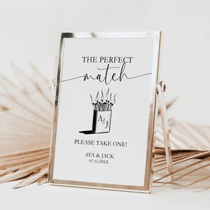 Peut inclure: Panneau encadré avec le texte "THE PERFECT match" au-dessus d'un dessin d'une boîte d'allumettes avec des allumettes allumées. En dessous, le texte "PLEASE TAKE ONE !" et les noms "AVA & JACK" avec une date.