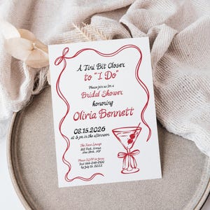 May include: White invitation card with red text and a decorative border. The card reads "A Tini Bit Closer to 'I Do'" and invites guests to a bridal shower honoring Olivia Bennett. Includes a cocktail illustration.