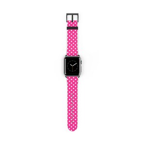 May include: A black smartwatch with a bright pink polka dot band. The band features a pattern of white dots on a pink background. The watch face is black with white hands. The band is made of a flexible material.