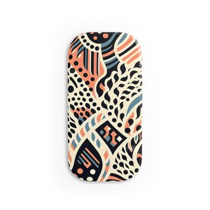 May include: A long, narrow, oval-shaped phone case with a colorful abstract pattern. The pattern features black, white, orange, and blue colors and includes geometric shapes, dots, and swirls.