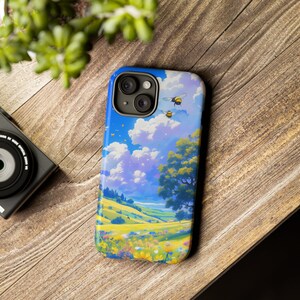 May include: A phone case with a colorful illustration of a field of flowers, a blue sky with clouds, and bees flying. The case has a camera cutout and a white background.