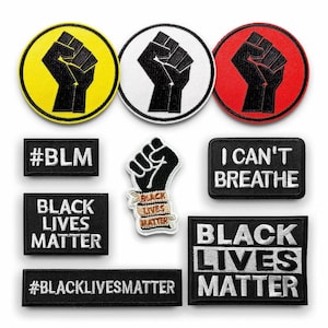 Op de afbeelding: Negen strijkbare patches met een zwart vuistontwerp en verschillende slogans, waaronder "Black Lives Matter", "#BLM", "I Can't Breathe" en "#BlackLivesMatter". De patches zijn in zwart, wit, geel en rood.