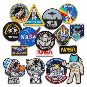 Könnte beinhalten: Eine Sammlung von 14 gestickten Bügeletiketten mit Weltraummotiven. Die Patches sind bunt und zeigen verschiedene NASA-Logos, Raumschiffe, Astronauten und UFOs. Die Patches sind perfekt, um Kleidung, Taschen oder anderen Gegenständen eine einzigartige Note zu verleihen.