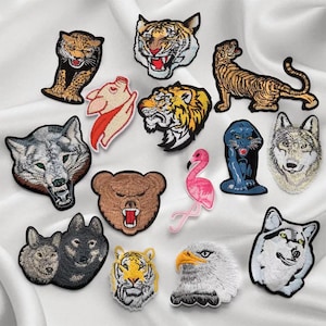 Op de afbeelding: Een verzameling geborduurde strijkpatches met verschillende dieren, waaronder een wolf, een tijger, een beer, een flamingo, een adelaar en een panter. De patches zijn kleurrijk en gedetailleerd, perfect om kleding, tassen of andere accessoires een unieke touch te geven.