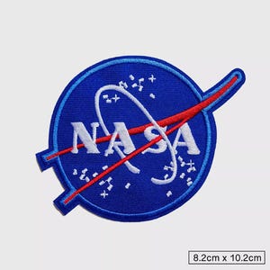 Könnte beinhalten: Ein blauer und roter gestickter Aufnäher mit dem NASA-Logo und einer weißen Umlaufbahn um einen blauen Kreis. Der Aufnäher ist 8,2 cm x 10,2 cm groß.