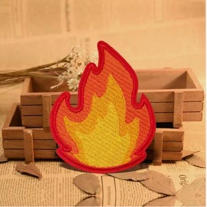 May include: Red and yellow embroidered iron-on patch of a flame design.