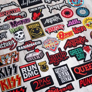May include: A collection of colourful embroidered iron-on patches featuring various rock band logos, including Metallica, Led Zeppelin, Misfits, Nirvana, Anthrax, Testament, Black Sabbath, Korn, Rammstein, Doctor Who, Lamb of God, Green Day, Queen, and 2Pac.