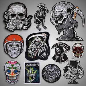 Op de afbeelding: Een verzameling van tien strijkbare patches met verschillende schedelontwerpen. De patches zijn in zwart, wit en grijs met enkele rode, blauwe en groene accenten. Sommige patches bevatten tekst, waaronder "Stoked" en "不運の時代".