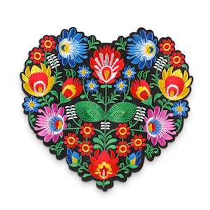 Può includere: Una toppa ricamata a forma di cuore con un motivo floreale colorato. La toppa presenta fiori rossi, gialli, blu, verdi e rosa su uno sfondo nero.