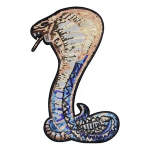 May include: A gold and blue sequined cobra snake iron-on patch. The snake is in a coiled position with its head raised.