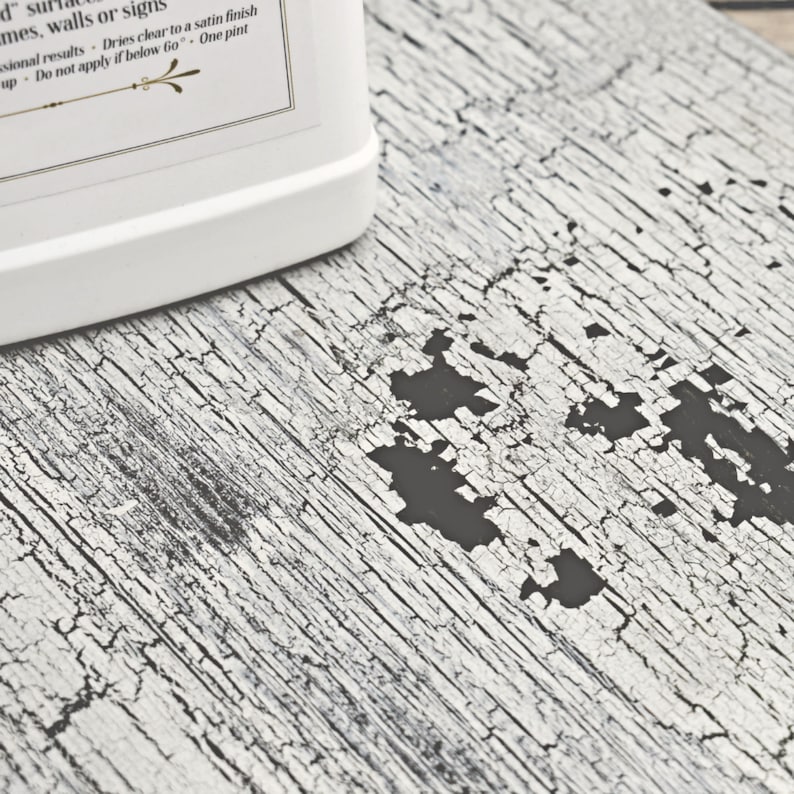 May include: A white plastic bottle with a black label and text that reads "Dries clear to a satin finish - One pint". The bottle is sitting on a white surface with a black cracked pattern.