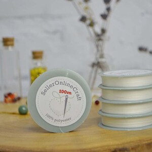 a stack of white spools of thread sitting on a wooden table
