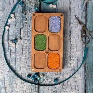a wooden box filled with beads and a pair of scissors
