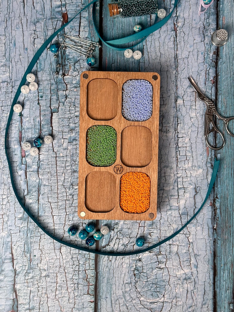 a wooden box filled with beads and a pair of scissors