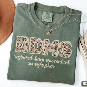 May include: A green t-shirt with the text "RDMS registered diagnostic medical sonographer" in a brown leopard print font.