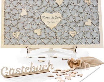 May include: A wooden guest book with a heart-shaped design. The guest book is on a stand and has a sign that says "Gästebuch". There are also a number of small wooden hearts scattered around the guest book.
