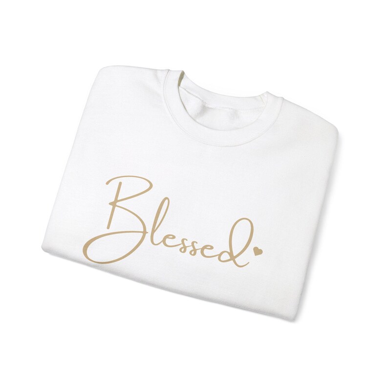 May include: White t-shirt with the word "Blessed" written in gold cursive script.