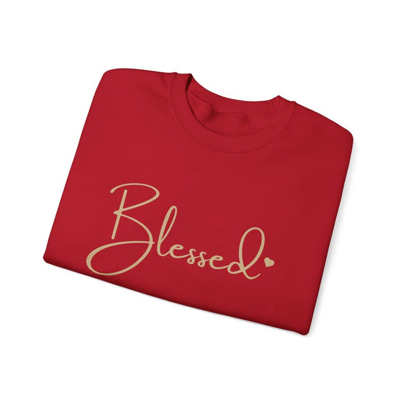 May include: Red t-shirt with the word "Blessed" written in gold script with a small heart next to it.