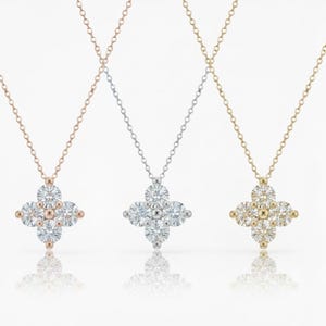 May include: Three necklaces with clover-shaped pendants, each with sparkling gemstones. The pendants are in rose gold, silver, and gold. Each necklace has a fine chain. The pendants are a popular design.