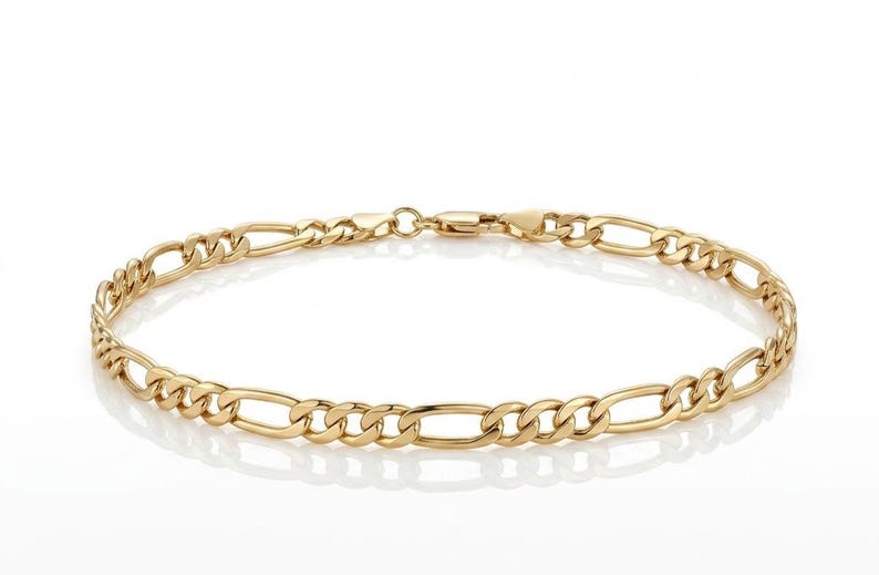 Pu&ograve; includere: Un braccialetto con catena Figaro color oro. Il braccialetto presenta un motivo di tre piccoli anelli circolari seguiti da un anello ovale allungato. Il braccialetto &egrave; esposto su sfondo bianco.