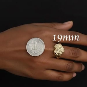 Puede incluir: Un anillo dorado con un dise&ntilde;o org&aacute;nico texturizado, junto a una moneda para comparar el tama&ntilde;o. El anillo tiene aproximadamente 19 mm de di&aacute;metro. Fondo oscuro.