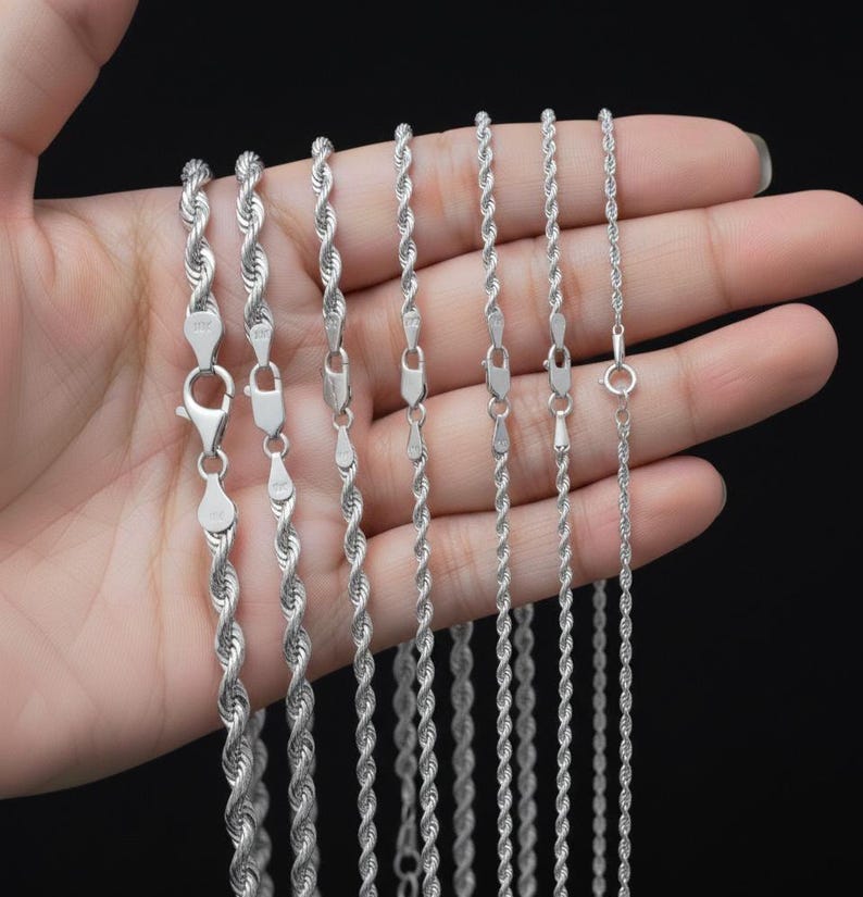 Puede incluir: Varias cadenas de plata tipo cuerda de diferentes grosores. Cada cadena tiene un cierre de mosquet&oacute;n. Las cadenas se muestran sobre un fondo oscuro.