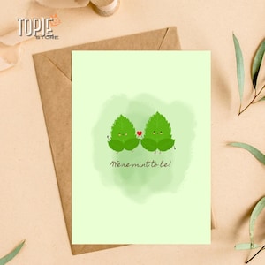 Puede incluir: Una tarjeta verde claro con dos hojas de menta de dibujos animados que sostienen un corazón rojo. El texto en la tarjeta dice "We're mint to be!"