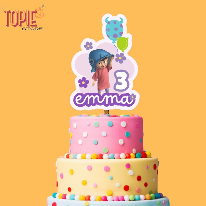 May include: A pink and yellow cake with colorful sprinkles. A cake topper features a cartoon girl with purple hair and a blue hat, with the text "emma" and the number "3" in purple.