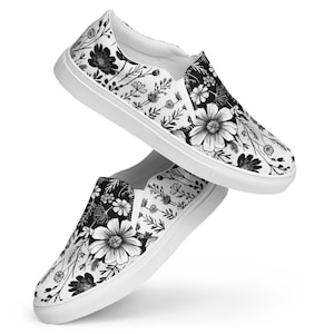 May include: White slip-on shoes with a black and white floral design. The pattern includes various flowers and leaves, giving a botanical theme. The shoes have a white sole and a casual style, suitable for everyday wear.