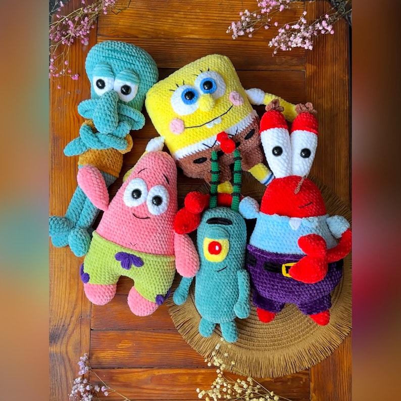 May include: A collection of five crocheted plush toys featuring characters from SpongeBob SquarePants: a teal Squidward, a yellow SpongeBob, a pink Patrick Star, a small green Plankton, and a red Mr. Krabs, all crafted with soft yarn textures.