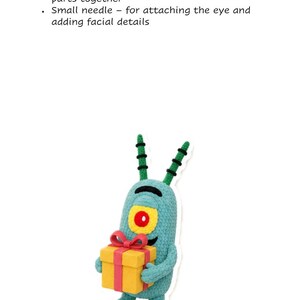 May include: A teal crocheted character with two antennae, a single large yellow and red eye, and small arms holding a yellow gift box with a red ribbon. Above the character, text reads: 10. Needles: Large-eye tapestry needle - for sewing parts together, Small needle - for attaching the eye and adding facial details.
