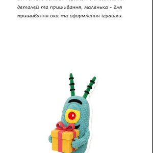 May include: A light blue crocheted character with two antennae, a single large yellow eye with a red pupil, and a black curved mouth. The character holds a yellow gift box with a red ribbon and bow. Text above reads 9. Швейні шпильки. 10. Голка з великим вушком для зшивання деталей та пришивання, маленька - для пришивання ока та оформлення іграшки.