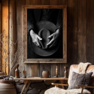 Pu&ograve; includere: Fotografia in bianco e nero di mani che tengono un cappello a tesa larga. Il cappello &egrave; fatto di un materiale scuro e ha una superficie leggermente strutturata. Le mani della persona sono visibili nell'immagine e stanno tenendo il cappello in un modo che suggerisce che stanno per metterlo.