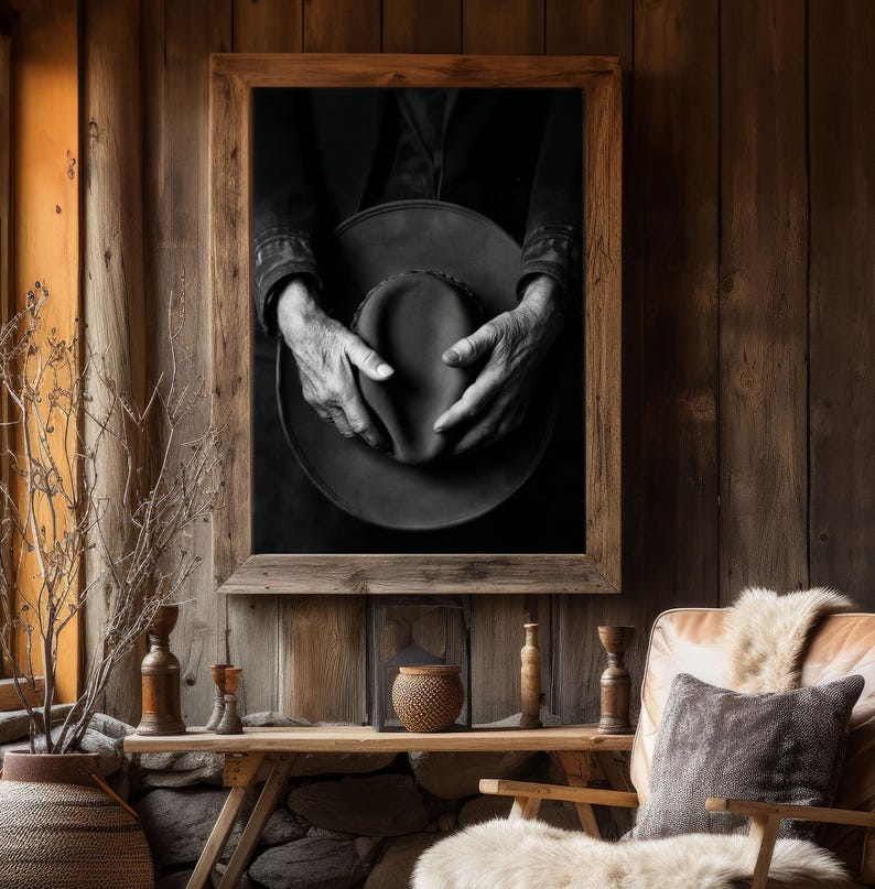Pu&ograve; includere: Fotografia in bianco e nero di mani che tengono un cappello a tesa larga. Il cappello &egrave; fatto di un materiale scuro e ha una superficie leggermente strutturata. Le mani della persona sono visibili nell'immagine e stanno tenendo il cappello in un modo che suggerisce che stanno per metterlo.
