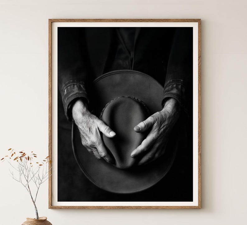 Pu&ograve; includere: Una fotografia in bianco e nero di mani che tengono un cappello a tesa larga. Il cappello &egrave; fatto di un materiale strutturato e le mani della persona sono rugose e mostrano segni di et&agrave;.