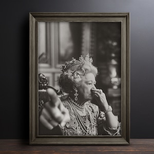 May include: A black and white portrait of a woman wearing a crown and a pearl necklace. She is looking at the camera and has her hand to her nose.