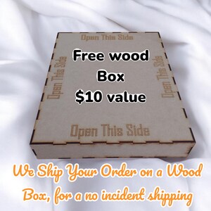 K&ouml;nnte beinhalten: Eine hellbraune Holzkiste mit dem Text "Free wood Box $10 value" in Schwarz. Auf der Kiste stehen die Worte "Open This Side" auf den Seiten. Die Kiste steht auf einer wei&szlig;en Oberfl&auml;che.