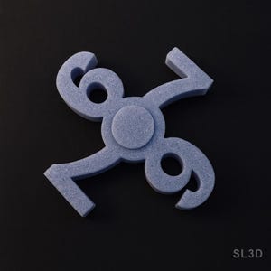 May include: A light blue, textured, 3D-printed object featuring the numbers 6, 7, 8, and 9 arranged in a circular pattern. The object has a matte finish and is set against a black background. The text "SL3D" is visible in the bottom right corner.