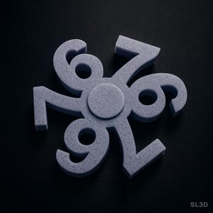 May include: A gray, 3D-printed fidget spinner with the numbers 6, 7, and 9 arranged in a circular pattern. The numbers are connected at a central hub. The background is black.