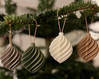 May include: Four matte-finish, spiral-shaped ornaments in muted earth tones of grey, sage green, cream, and tan. Each ornament features a pointed bottom, a rounded top with a small loop, and a thin, light-coloured string attached for hanging purposes.