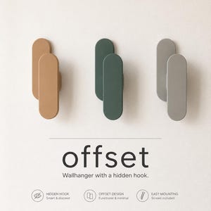 May include: Three wall hooks in tan, dark green, and grey, each featuring an elongated oval shape with an offset design. The text reads: offset, Wallhanger with a hidden hook, HIDDEN HOOK Smart & discreet, OFFSET DESIGN Functional & minimal, EASY MOUNTING Screws included.